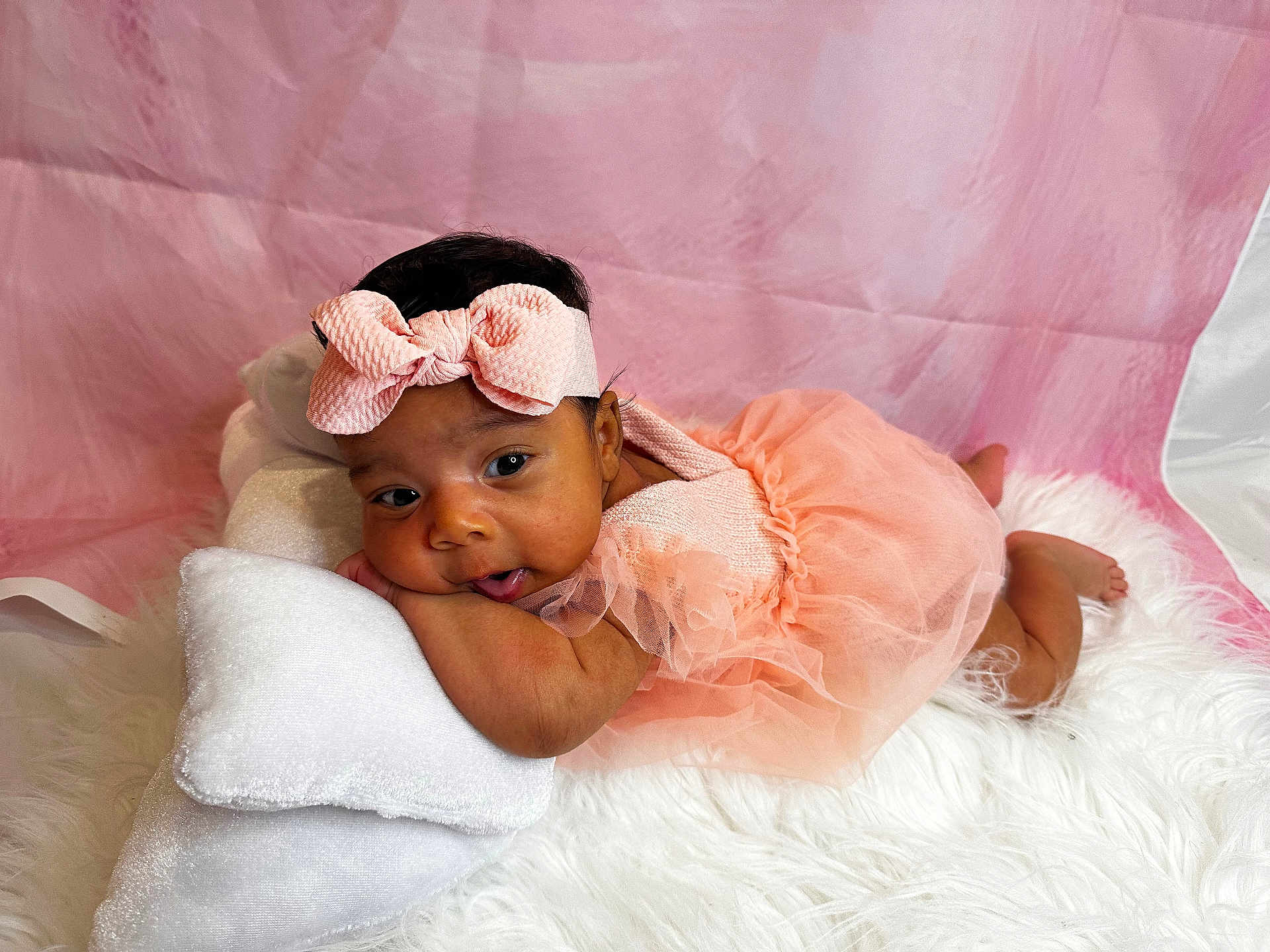 Aloura joined the competition — help win amazing prizes! baby, infant, girl, headband, bow, pink_dress, tulle, pillow, white_rug, soft_texture, portrait, cute, resting, curious, indoor, child, smiling, pink_background, closeup, adorable