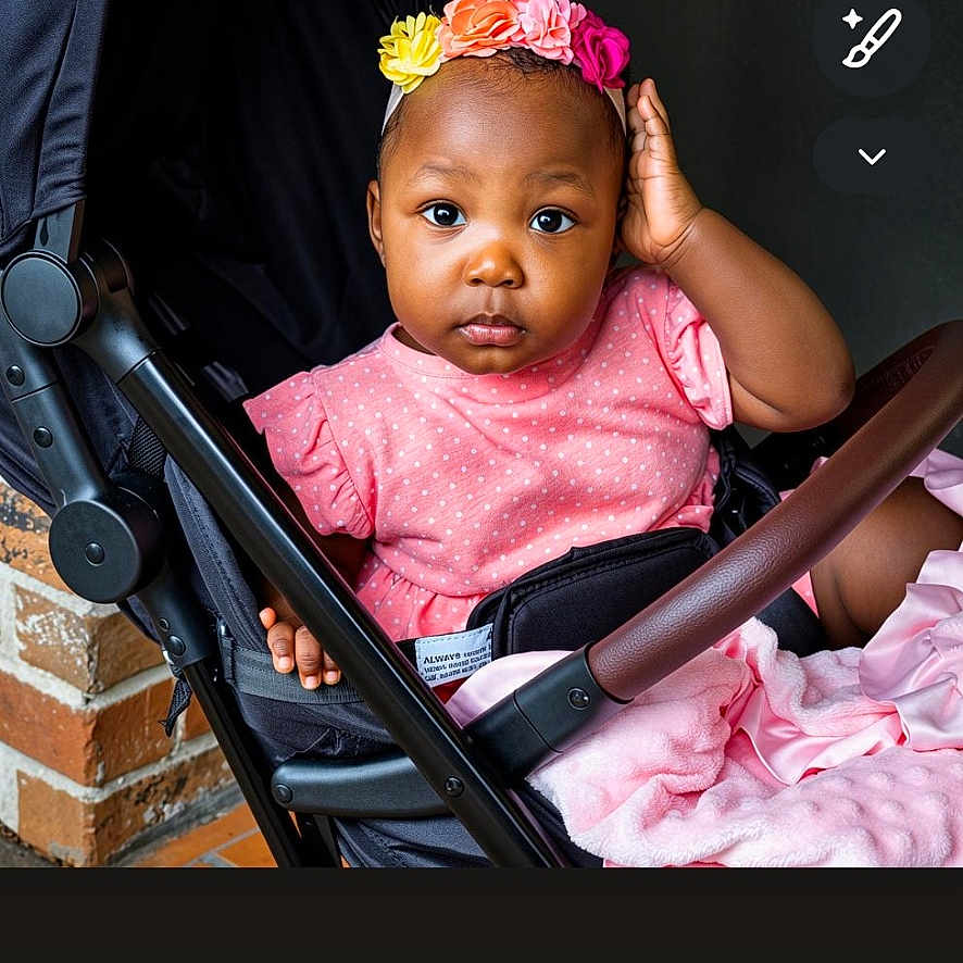 Brennayah joined the competition — help win amazing prizes! baby, baby_girl, brick_wall, casual, child, colorful, curious, cute, expression, flower_headband, girl, headwear, indoors, infant, person, pink_dress, portrait, seated, stroller, young_child