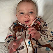 Isaiah is registered to the contest to win money with this photo: baby, infant, child, portrait, face, hand, clothing, pajamas, pattern, western_style, horse, flower, button, bed, pillow, blanket, expression, cute, indoors, soft_lighting