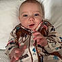 baby, infant, child, portrait, face, hand, clothing, pajamas, pattern, western_style, horse, flower, button, bed, pillow, blanket, expression, cute, indoors, soft_lighting