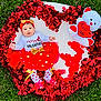 baby, infant, red_tutu, headband, teddy_bear, valentine, heart_shape, blanket, grass, outdoor, red_garland, petals, cute, festive, smiling, celebration, holiday, child, portrait, adorable