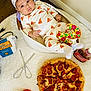 baby, infant, pizza_outfit, bandana, basket, pepperoni_pizza, tomatoes, flour_bag, kitchen_utensils, whisks, ketchup_bottle, white_blanket, floor, food, cute, child, indoors, portrait, food_ingredients, cozy
