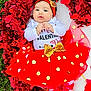 baby, infant, valentines_day, red_tutu, gold_bow, headband, festive, holiday_decor, heart_shaped, tinsel, grass, blanket, cute, smiling, portrait, clothing, celebration, lying_down, toddler, child