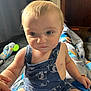 Kai is registered to the contest to win money with this photo: baby, child, romper, blue_clothing, indoor, toy, blanket, curious, sitting, hand, face, eyes, skin, hair, furniture, cozy, infant, cute, expression, home