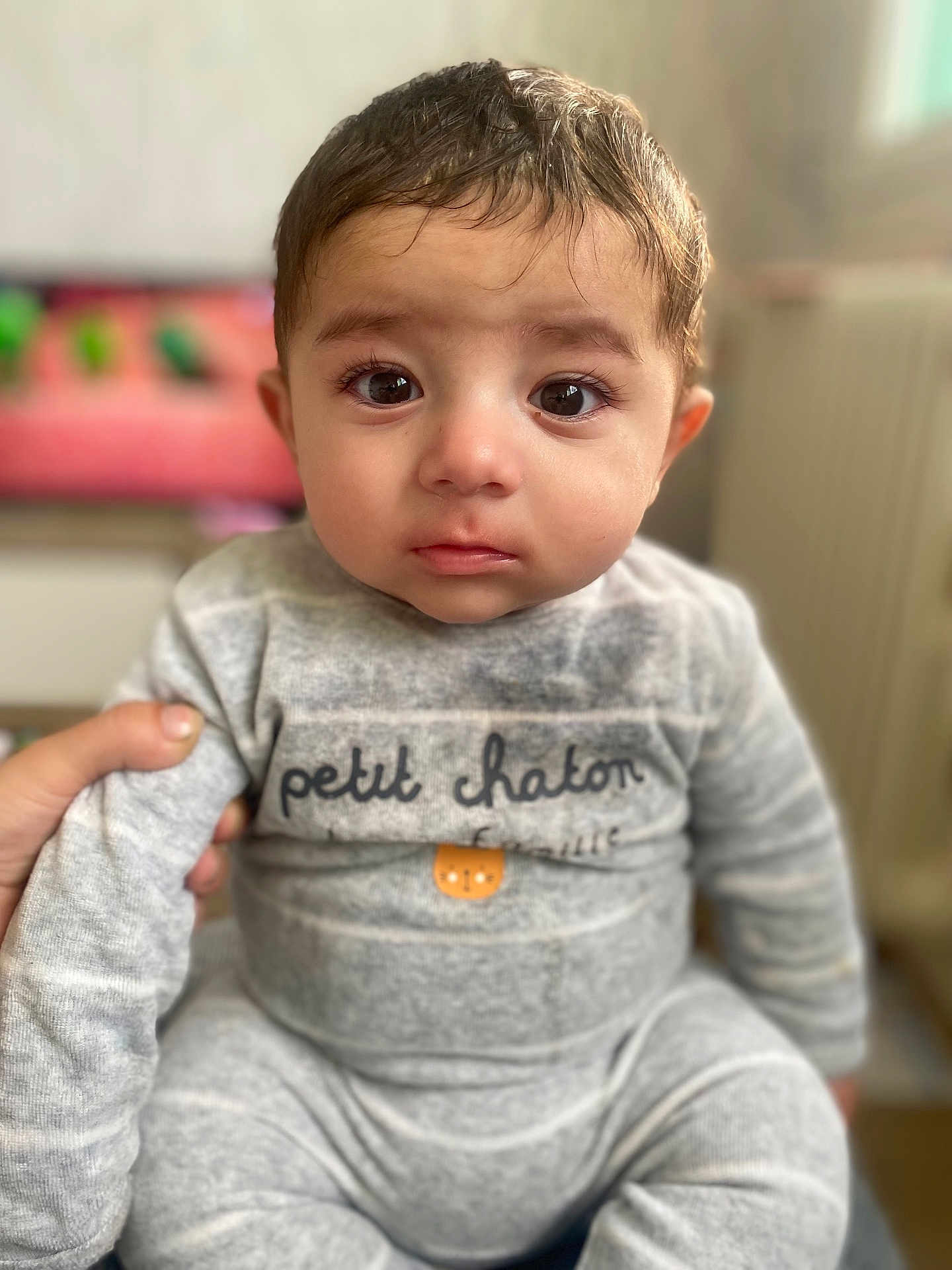 Kenan participe au concours pour gagner de l'argent avec cette photo : baby, child, face, eyes, expression, gray_clothing, sitting, hand, indoors, portrait, cute, young_child, infant, soft_light, cozy, warm_tones, person, closeup, human, apparel