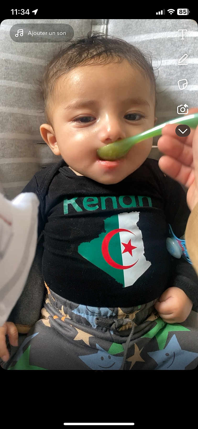 Kenan participe au concours pour gagner de l'argent avec cette photo : baby, child, feeding, spoon, black_shirt, algerian_flag, cushion, striped_background, pants, stars_pattern, hand, closeup, indoor, person, infant, cute, relaxed, food, apparel, portrait