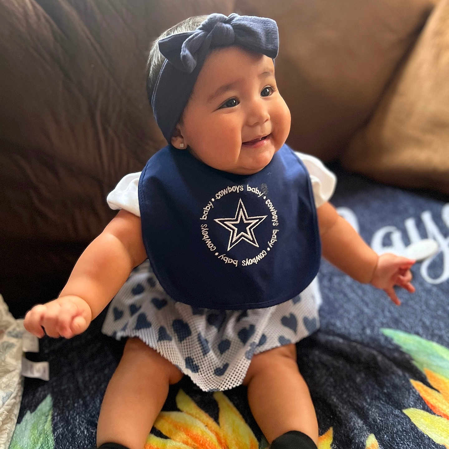Harmony is registered to the contest to win money with this photo: baby, babylaughing, bonnet, cap, clothing, couch, cushion, dress, face, happy, hat, head, homedecor, hosiery, pants, person, photography, portrait, sitting, sock