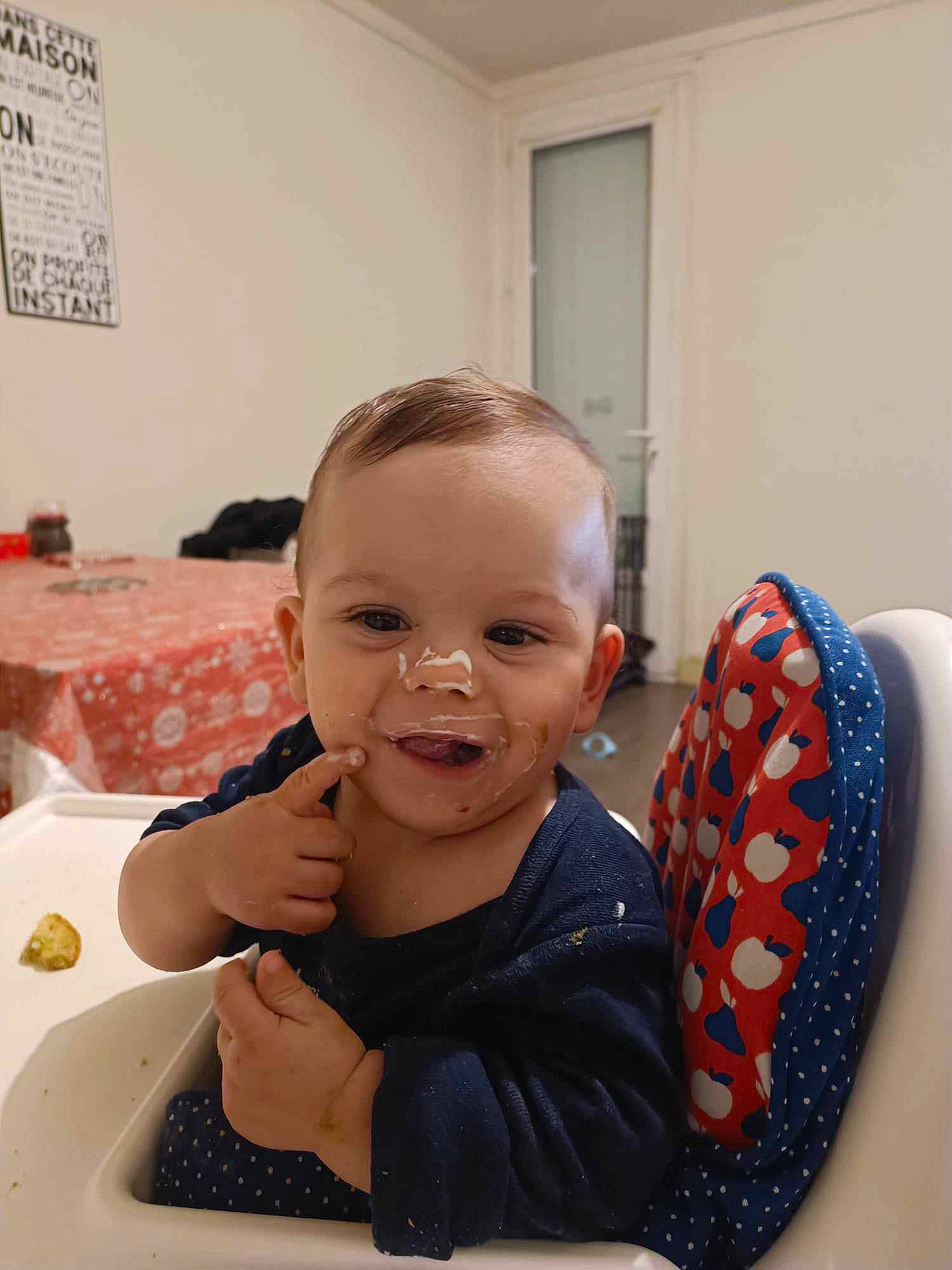 Gabriel participe au concours pour gagner de l'argent avec cette photo : arm, baby, baby_toddler_clothing, carmine, chair, cheek, child, event, finger, fun, hairstyle, happy, mouth, person, room, sitting, skin, smile, table, thumb