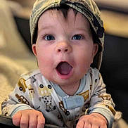 Oliver is registered to the contest to win money with this photo: baby, child, cap, pajamas, hands, face, blue_eyes, expression, playpen, crib, indoor, portrait, cute, infant, grip, clothing, young, surprised, headwear, soft_background