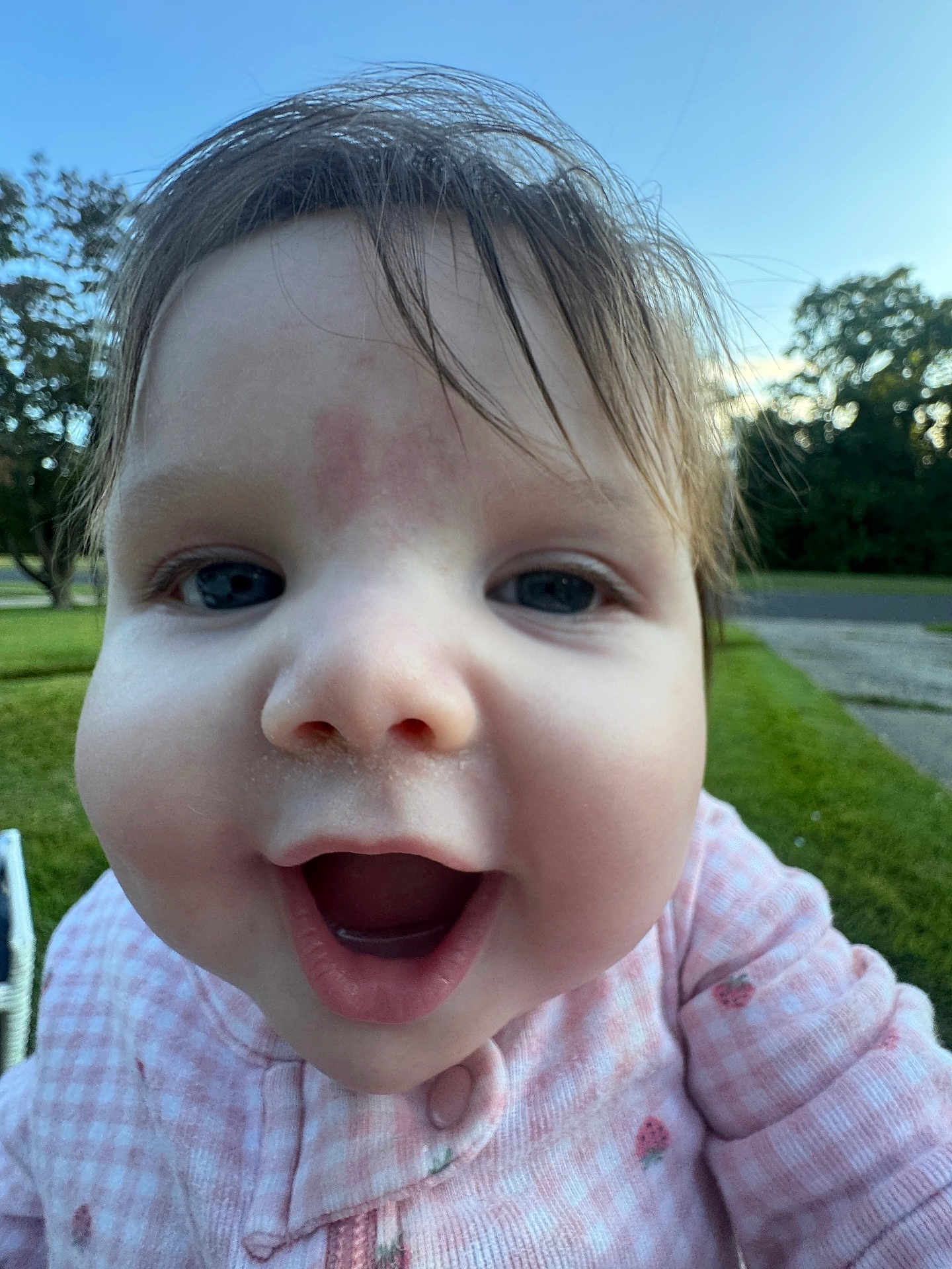 Ariel is registered to the contest to win money with this photo: baby, child, face, close_up, pink_clothing, outdoor, grass, trees, sky, happy, smiling, mouth_open, cute, infant, portrait, young_child, nature, daylight, person, head