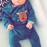 Lissandro participe au concours pour gagner de l'argent avec cette photo : baby, infant, onesie, reindeer_patch, red_nose, blue_eyes, couch, pillow, patterned_pillow, footed_pajamas, cozy, portrait, newborn, cute, clothing, hands, legs, indoors, soft_fabric, gaze