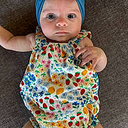 Lakelynn joined the competition — help win amazing prizes! baby, infant, child, headband, blue_headband, floral_romper, flower_pattern, colorful_clothing, lying_down, brown_background, cute, wide_eyes, portrait, skin, hand, legs, baby_fashion, closeup, indoors, soft_light