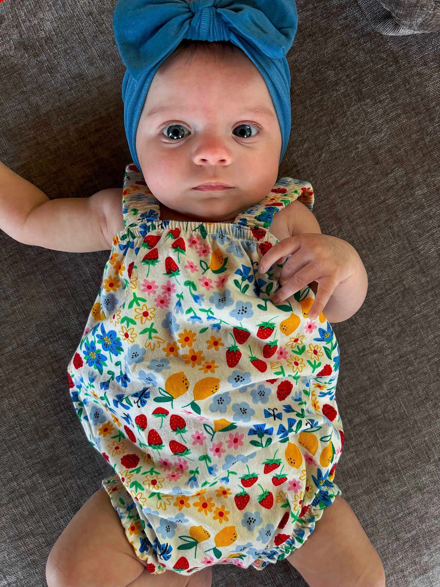 Lakelynn joined the competition — help win amazing prizes! baby, infant, child, headband, blue_headband, floral_romper, flower_pattern, colorful_clothing, lying_down, brown_background, cute, wide_eyes, portrait, skin, hand, legs, baby_fashion, closeup, indoors, soft_light