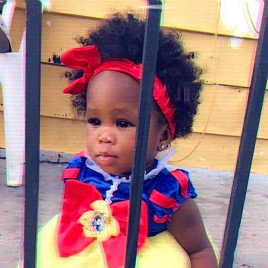 Imani is registered to the contest to win money with this photo: baby, child, costume, face, fashion_accessory, hair, hair_accessory, head, headgear, person, plant, smile, toddler