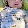 baby, infant, child, face, clothing, shirt, pants, blanket, pattern, car_print, lying_down, soft_toy, closeup, curious, skin, eyes, head, button, fabric, natural_light