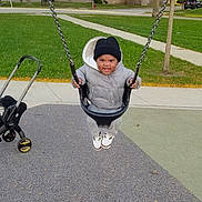 Keyon joined the competition — help win amazing prizes! baby, child, swing, playground, outdoor, smiling, winter_clothing, hat, jacket, shoes, grass, sidewalk, stroller, suburban, street, trees, houses, playground_surface, portrait, daylight