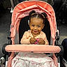 toddler, child, stroller, smiling, baby, toy, blanket, pink, hair_buns, cute, indoor, public_transport, people, clothing, happy, portrait, person, seat, transportation, urban