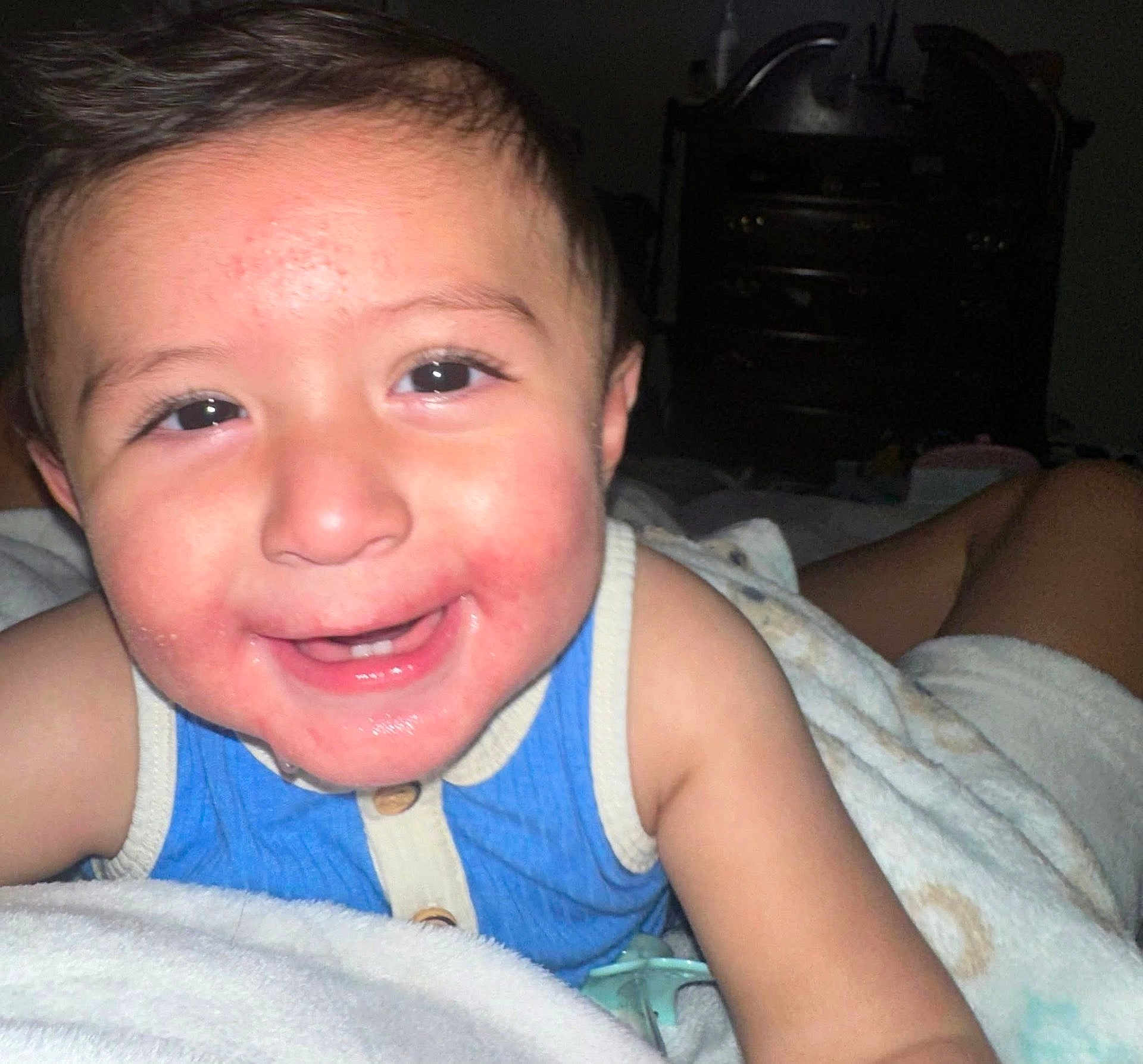 Damian joined the competition — help win amazing prizes! toddler, child, smiling, face, blue_clothing, blanket, indoors, portrait, happy, baby, skin, head, eyes, mouth, arm, furniture, darker_background, sleepwear, cozy, closeup