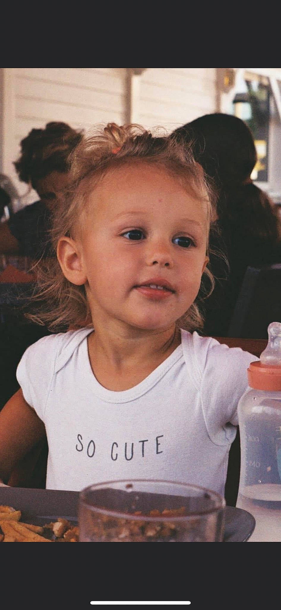 Inaya a rejoint le concours — aidez-le/la à gagner de superbes lots ! alcoholic_beverage, blond, cheek, child, drink, drinking, drinkware, eyelash, face, fun, happy, iris, nose, person, plastic_bottle, smile, t_shirt, tableware, toddler, wine