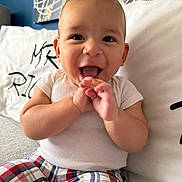 Liam joined the competition — help win amazing prizes! baby, background, child, clothing, couch, cute, face, hands, happy, home, indoor, infant, person, pillow, plaid_pants, portrait, sitting, smiling, white_shirt, young_child