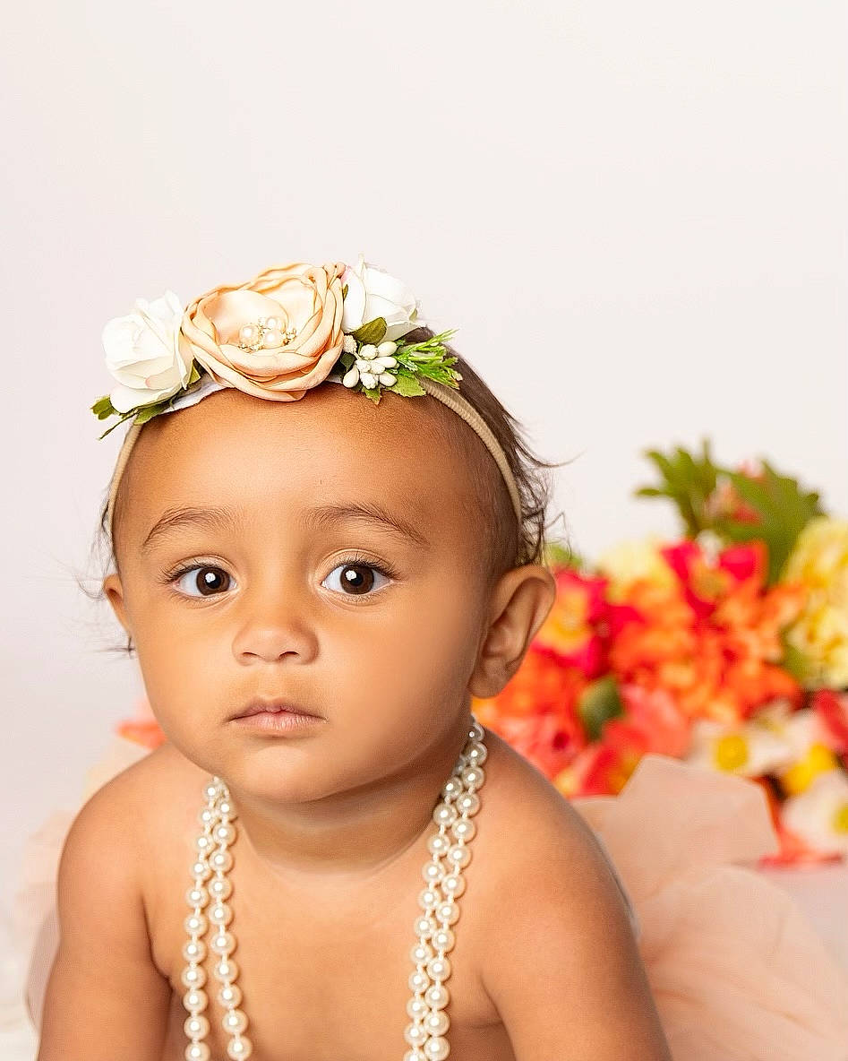 Jream is registered to the contest to win money with this photo: arm, baby, cheek, chin, eye, eyebrow, face, flash_photography, flower, hair, happy, head, headgear, headpiece, iris, lip, person, petal, plant, skin