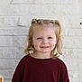 Ember is registered to the contest to win money with this photo: background, blonde_hair, casual_clothing, child, childhood, cute, face, fashion, girl, happy, indoor, light_skin, maroon_sweater, person, ponytails, portrait, smiling, standing, white_brick_wall, young_child