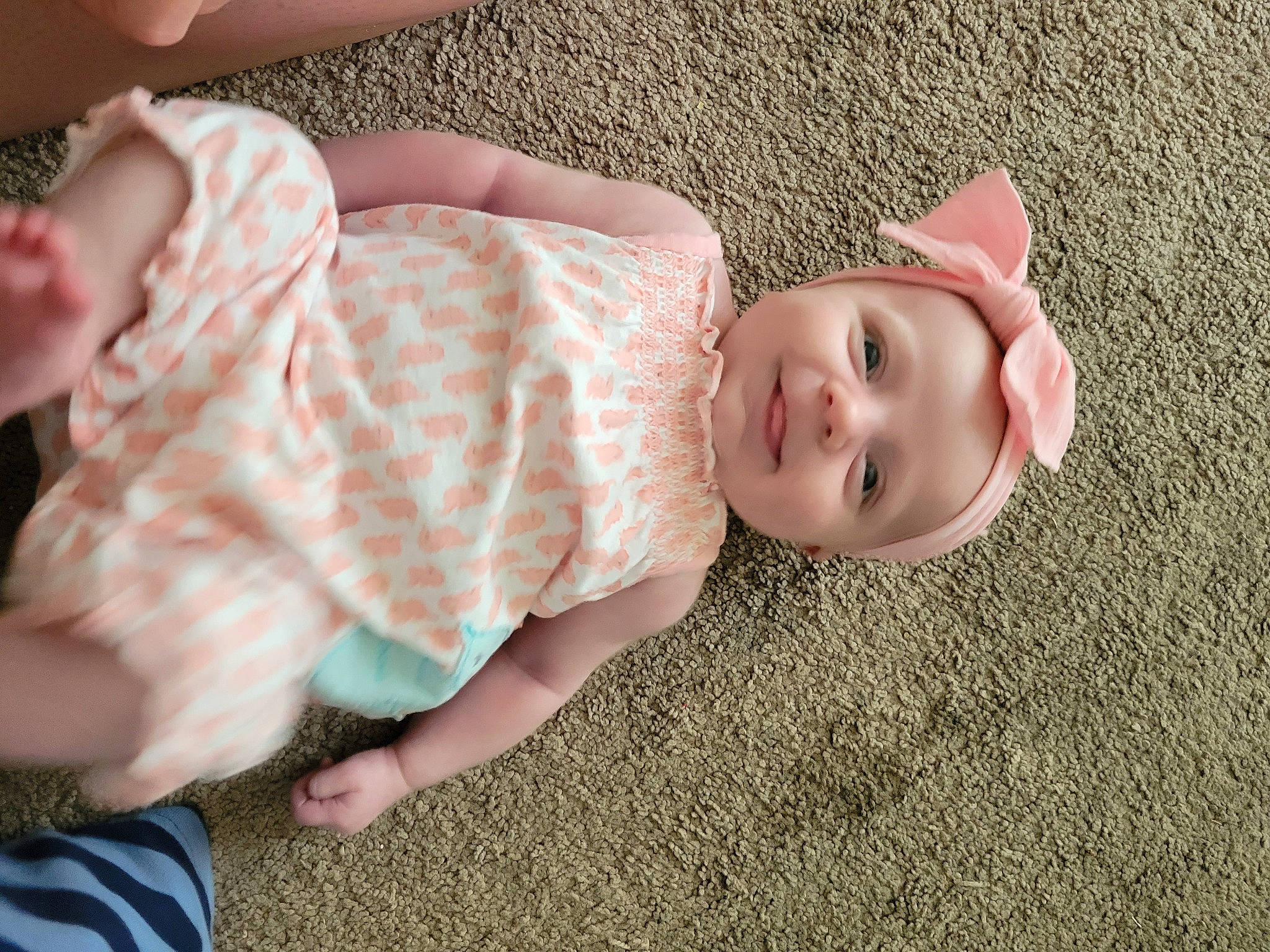 Ember is registered to the contest to win money with this photo: baby, baby_toddler_clothing, cheek, comfort, dress, eye, fawn, finger, flooring, grass, head, headgear, headwear, human_body, lip, nose, person, skin, sleeve, smile