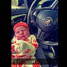 Jeremiah joined the competition — help win amazing prizes! newborn, baby, infant, sleeping, face, portrait, car, steering_wheel, cadillac, vehicle, red_hat, blanket, onesie, patterned_clothing, bundled, indoor, vehicle_interior, heart_text, text_overlay, cozy