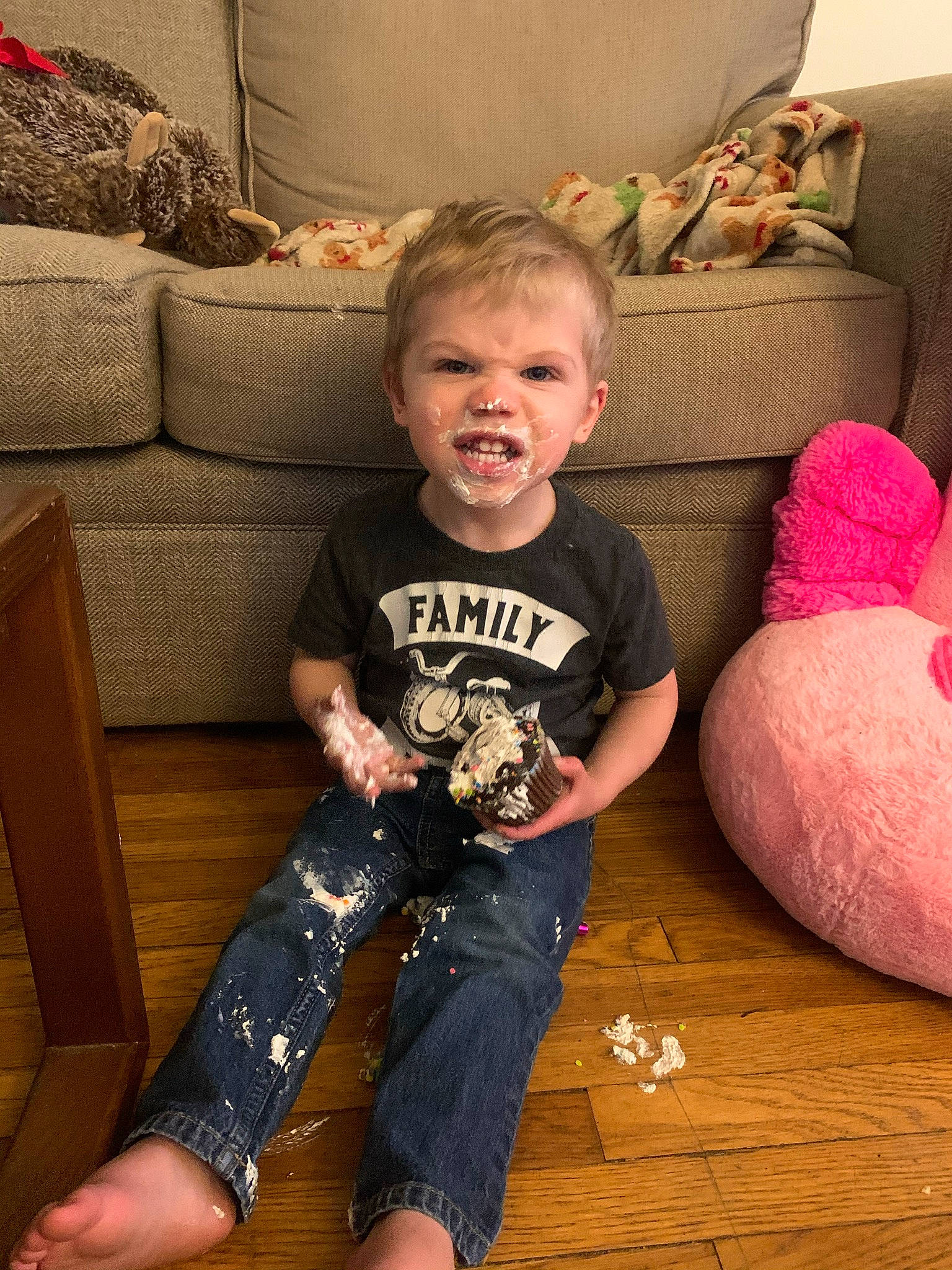 Sebastian is registered to the contest to win money with this photo: baby_toddler_clothing, child, comfort, couch, facial_expression, flooring, fun, hardwood, human_body, human_leg, knee, lap, leg, living_room, person, sitting, sleeve, t_shirt, thigh, toddler