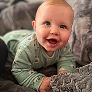 Lyam participe au concours pour gagner de l'argent avec cette photo : baby, child, smile, blue_eyes, green_clothing, blanket, soft_texture, cozy, indoor, portrait, happy, cute, infant, closeup, laying_down, young_child, warm, comfortable, face, expression
