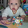 baby, child, play_mat, toy, colorful, indoor, curious, infant, face, hands, crawling, plastic_toy, home, young_child, expression, clothing, necklace, floor, bright, closeup