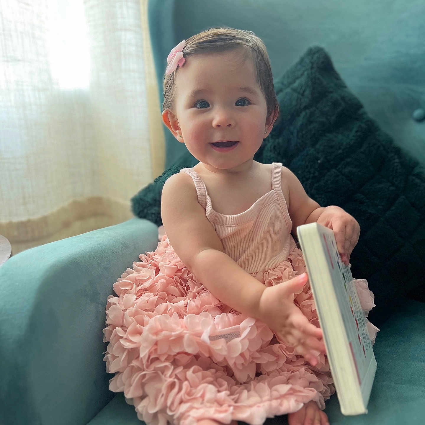 Elliana joined the competition — help win amazing prizes! armchair, baby, barefoot, book, child, cozy, curly_hair, curtains, cushion, cute, girl, hair_clip, happy, indoors, pink_dress, portrait, room, seated, smiling, soft_light