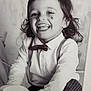 toddler, child, smile, bow_tie, suspenders, toy, black_and_white, portrait, happy, curly_hair, face, clothing, long_sleeve, cute, indoors, playful, person, young_child, joyful, classic