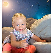 Lola participe au concours pour gagner de l'argent avec cette photo : blonde_hair, blue_eyes, carpet, child, cozy, cushions, cute, floral_top, happy, indoor, moon, pink_pants, portrait, reaching_out, sitting, smiling, soft_lighting, starry_background, toddler, young_child