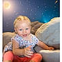 blonde_hair, blue_eyes, carpet, child, cozy, cushions, cute, floral_top, happy, indoor, moon, pink_pants, portrait, reaching_out, sitting, smiling, soft_lighting, starry_background, toddler, young_child