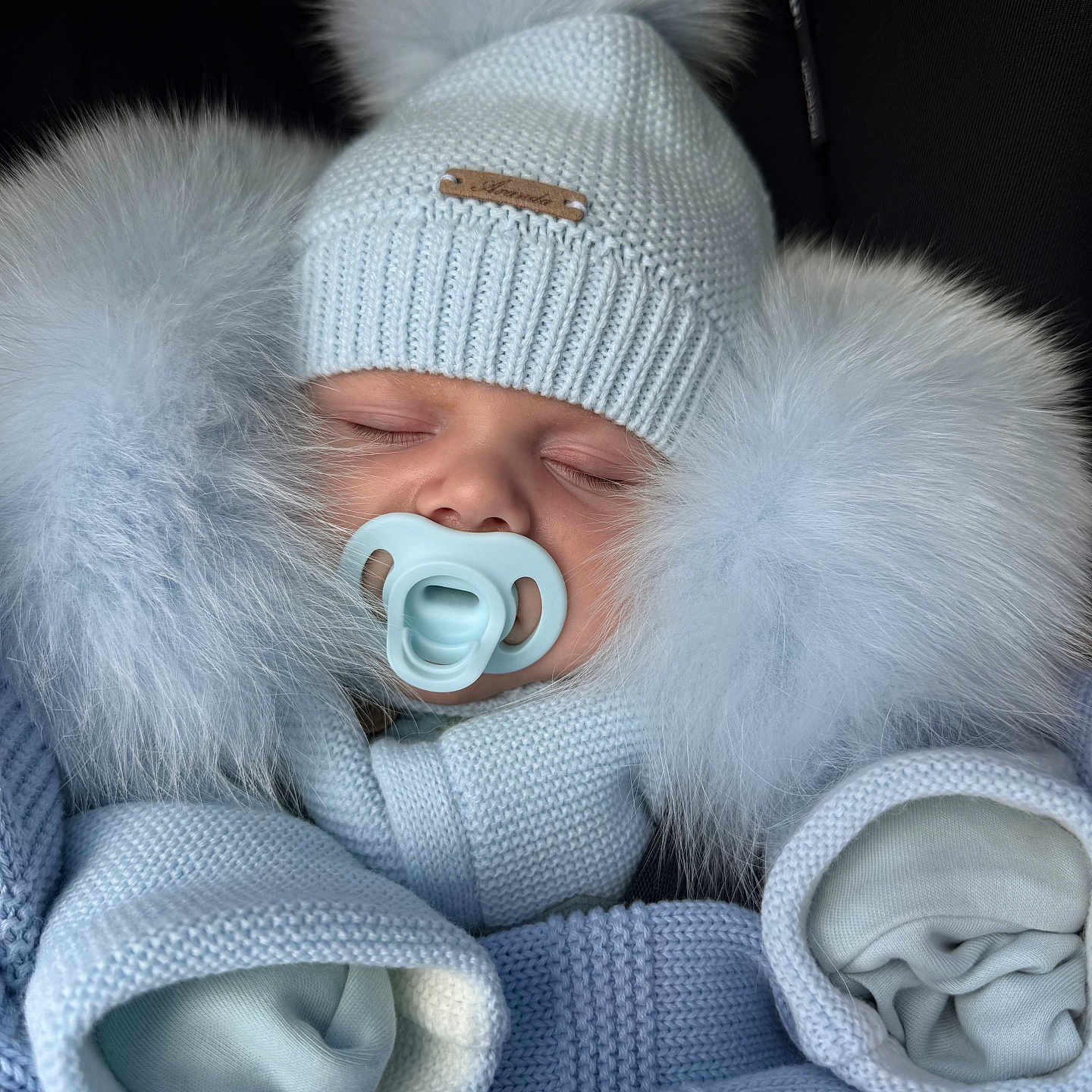 Arnie is registered to the contest to win money with this photo: baby, blue, bundle, child, closed_eyes, clothing, cozy, cute, face, hands_covered, hat, infant, knitwear, pacifier, pom_poms, portrait, sleeping, soft, warm, winter