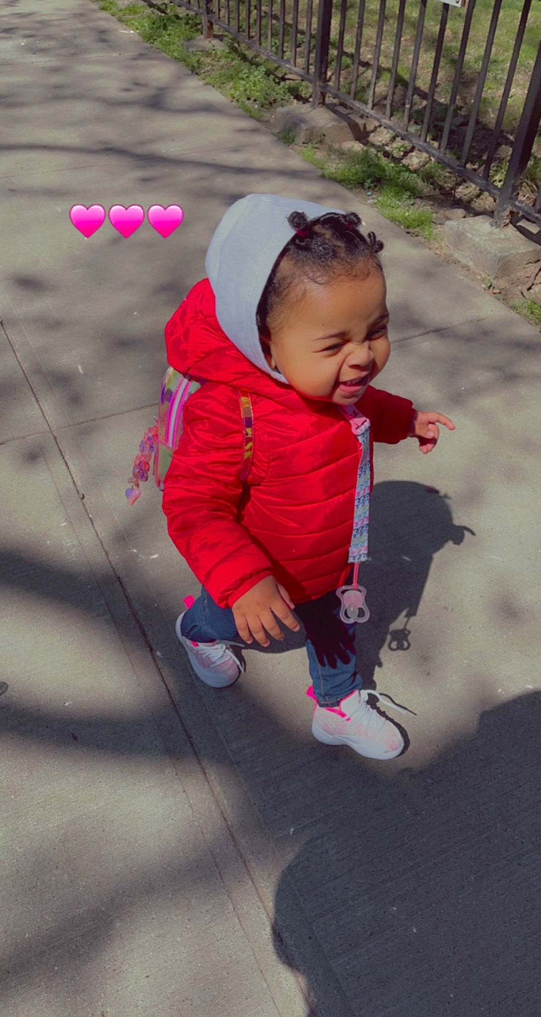 Maleah is registered to the contest to win money with this photo: asphalt, baby, baby_toddler_clothing, face, fun, grass, happy, head, leisure, magenta, person, pink, plant, play, recreation, road_surface, sidewalk, sitting, smile, toddler