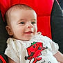 baby, infant, smiling, face, eyes, white_tshirt, cartoon, red, black, seat, clothing, cute, child, portrait, indoor, happy, person, head, young, candid