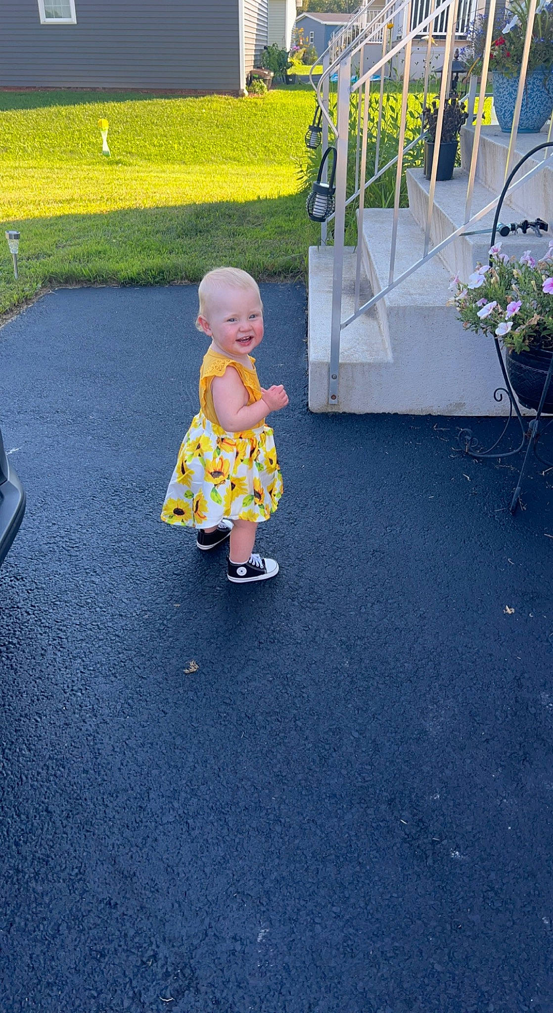 Kara is registered to the contest to win money with this photo: asphalt, baby, dress, electric_blue, flooring, flowerpot, fun, garden, grass, human_leg, leisure, pattern, person, plant, recreation, road_surface, sidewalk, sitting, toddler, toy