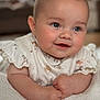 baby, infant, smile, blue_eyes, rosy_cheeks, white_blanket, ruffled_sleeves, animal_print, soft_focus, close_up, cute, portrait, child, resting, indoors, warm_lighting, happy, skin, hands, expression
