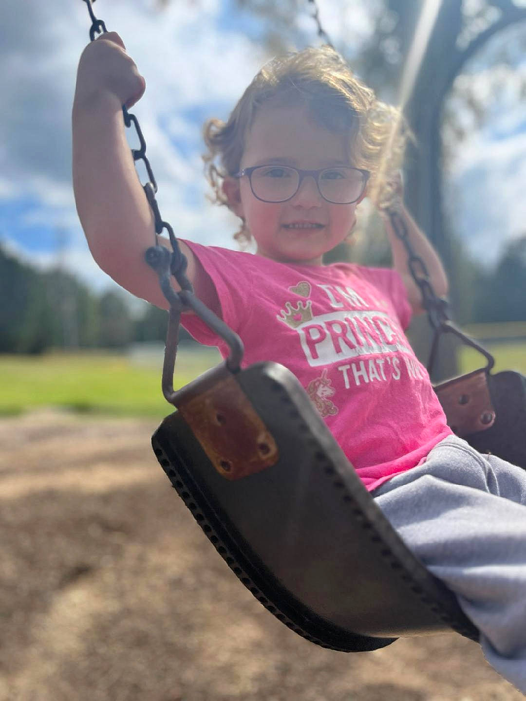 Emmarie joined the competition — help win amazing prizes! child, cloud, eyewear, fun, grass, happy, leisure, outdoor_play_equipment, person, plant, playground, recreation, sitting, sky, soil, summer, swing, tints_and_shades, toddler, travel