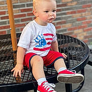 Presley is registered to the contest to win money with this photo: boy, brick_wall, casual_clothing, child, concrete_floor, daylight, handprint, metal_table, outdoor, portrait, red_shorts, red_sneakers, short_hair, sitting, socks, table, thoughtful, toddler, white_tshirt, young_child