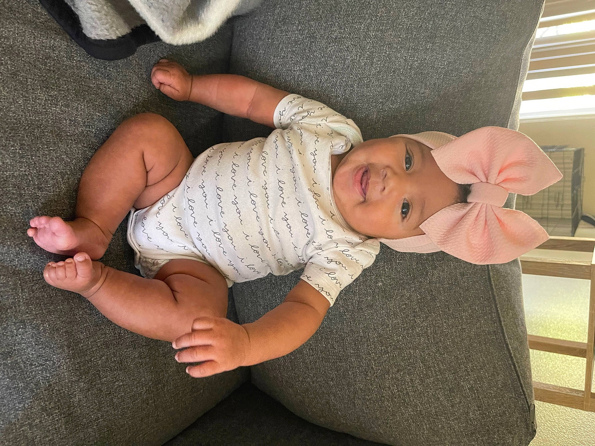 Indy is registered to the contest to win money with this photo: baby, baby_toddler_clothing, barefoot, comfort, elbow, eye, finger, foot, gesture, hat, headwear, human_body, human_leg, joint, knee, lap, person, skin, smile, textile