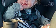 Haisley is registered to the contest to win money with this photo: toddler, child, car_seat, smiling, happy, clothing, seatbelt, hair_bow, striped_pants, finger, sunlight, indoors, car_interior, cute, person, baby, seat, sitting, playful, face