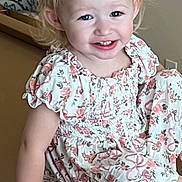 Maranda is registered to the contest to win money with this photo: toddler, child, smile, blonde_hair, dress, floral_pattern, sitting, indoor, happy, person, hand, face, cute, young_child, skin, arm, portrait, furniture, light, casual