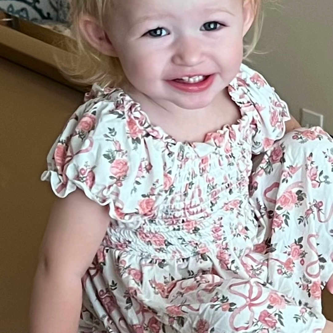 Maranda is registered to the contest to win money with this photo: arm, blonde_hair, casual, child, cute, dress, face, floral_pattern, furniture, hand, happy, indoor, light, person, portrait, sitting, skin, smile, toddler, young_child