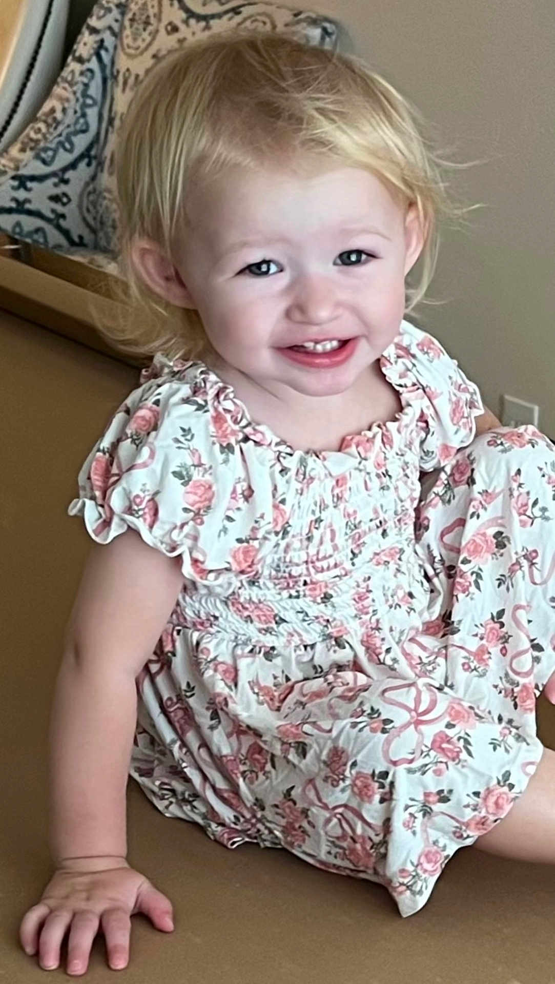 Maranda is registered to the contest to win money with this photo: toddler, child, smile, blonde_hair, dress, floral_pattern, sitting, indoor, happy, person, hand, face, cute, young_child, skin, arm, portrait, furniture, light, casual