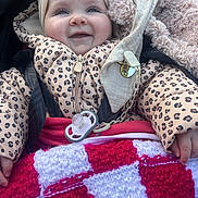 Mélyana participe au concours pour gagner de l'argent avec cette photo : baby, blanket, child, clothing, cute, face, hand, happy, headband, infant, jacket, knitted, leopard_print, outdoor, pacifier, red, smiling, stroller, warm, white