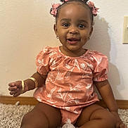 Jahlori is registered to the contest to win money with this photo: toddler, child, smiling, pink_bows, floral_outfit, carpet, sitting, happy, indoor, cute, person, footwear, bracelet, earrings, skin, hair, baby, portrait, young_child, joy