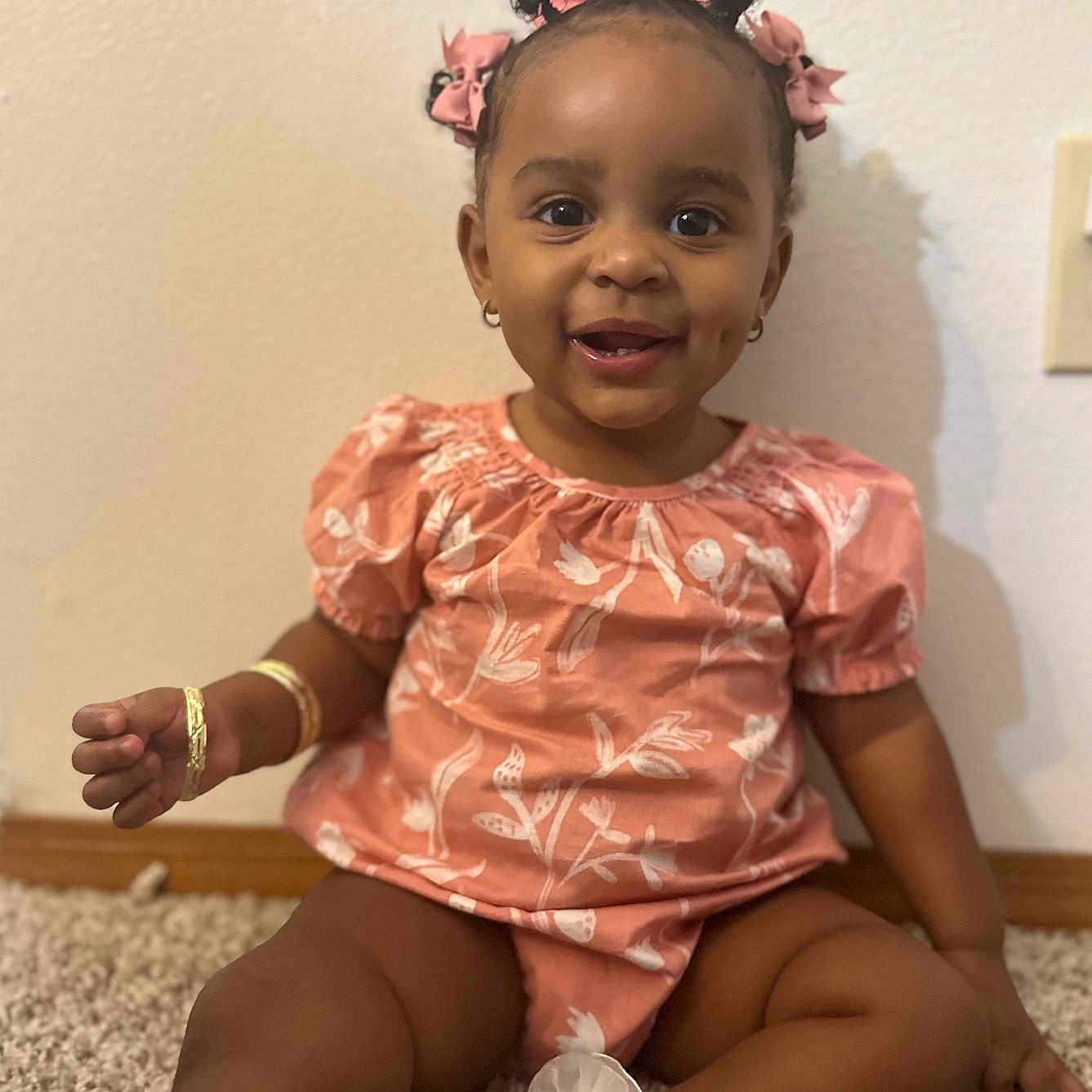 Jahlori is registered to the contest to win money with this photo: baby, bracelet, carpet, child, cute, earrings, floral_outfit, footwear, hair, happy, indoor, joy, person, pink_bows, portrait, sitting, skin, smiling, toddler, young_child